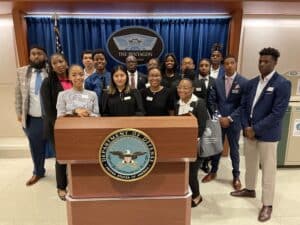 Group of HBCU students participating in Georgetown's Security Studies Summer Institute for HBCU Students surrounding a podium at the Department of Defense.